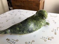 Front and side view of the green soapstone seal carving showing the polished surface and detailed shape.