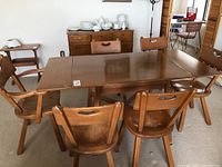 Full view of rectangular wooden dining table with six matching chairs placed around it.