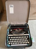 Photo of vintage Brother manual typewriter inside carrying case, showing overall condition and typewriter keyboard.