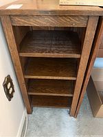 Front view of a solid wood wooden shelf unit showing four shelves and wear marks inside the unit.