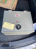 Front view of a gray metal safe with combination lock dial and a code instruction tag.