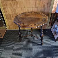 Solid oak hexagonal end table, carved tabletop with floral and scroll motifs, turned legs connected by stretchers