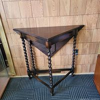 Side view of the vintage oak corner gateleg table showing the foldable triangular top and barley twist legs.