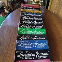 Stack of nine 1967 issues of Lapidary Journal on a round table, showing colorful covers from January through December 1967 except one month missing.