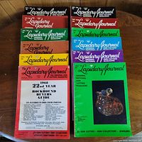 Photo showing 12 colorful Lapidary Journal magazines from 1968 arranged on a wooden surface.