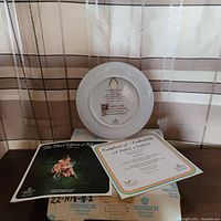 Rear view of the collector plate with backstamp and certificate of authenticity alongside booklet