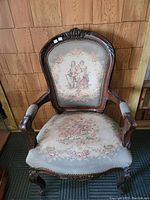Front view of antique French Victorian parlor chair showing carved wooden frame and tapestry upholstery with romantic couple and floral designs.