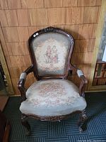 Front view of antique French Victorian parlor chair showing carved wood frame and upholstered fabric with romantic scene and floral design.