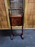Front view of antique wooden smoking stand with carved circular door and turned legs