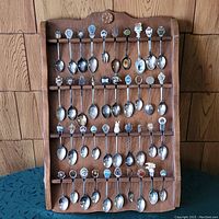 Full view of wooden rack holding 40 souvenir spoons arranged in rows, showing size and overall collection