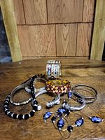 Photo of various costume jewelry pieces including bracelets and a necklace displayed on a wooden surface with a wooden background.
