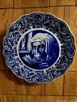 Front view of the decorative wall plate showing detailed blue portrait and floral border design