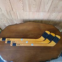 Three mini New York Rangers hockey sticks laid out side by side showing full length with logos and taped blades.