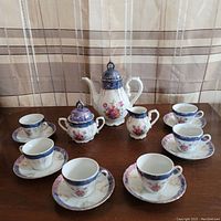 Full view of tea set including teapot, sugar bowl, creamer, six cups and six saucers arranged on table