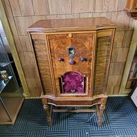 Full front view of the 1938 DeForest Crosley tube radio showing wooden cabinet, tapered legs, fabric-covered speaker door, and control knobs.