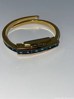 Gold-tone ladies bracelet watch lying flat, showing the hinged flip front with blue enamel and gold stars and small figures.