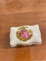 Top view of the rectangular white porcelain box showing the hand painted romantic lovers scene on the lid with gold accents on the edges.