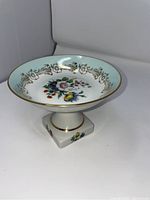 Angled side view of antique French Limoges handpainted candy dish showing floral design, gold accents, and pedestal base