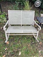 Front view of neutral toned metal framed outdoor rocking loveseat with mesh seat and backrest.