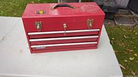Closed view of red steel toolbox showing overall condition, latches, and handle.