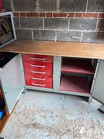 Front view of open cabinet doors showing five red heavy duty pull-out drawers on left and two adjustable shelves on right inside a stainless steel cabinet with wooden top.