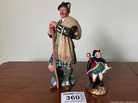 Two Royal Doulton figurines, The Laird and The Town Crier, displayed on a wooden surface.