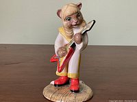 Front view of the Beswick cat figurine holding red electric guitar on textured base