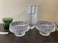 Photo showing five vintage mid-century glass candle holders with two clear ring-shaped Dansk holders, a tall Kosta Boda clear textured vase, green two-piece Dansk holder and a clear flower-shaped candle holder