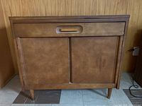 Front view of the wood console table showing the drawer and closed cabinet doors with a rectangular recessed handle.