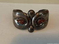 Front view of the silver cuff bracelet showing two brownish-red glittering stones inset with the silver band forming a curved design.