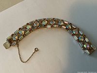 Full length view of bracelet on white background showing overall design and safety chain.