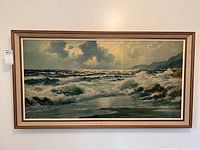 Full view of framed seascape painting showing turbulent waves, rocks, and cloudy sky