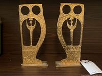 Front view of both antique brass bookends with intricate cutouts and Greek patterns.