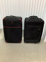 Two full sized luggage pieces side by side, black fabric with different accent colors and pocket designs.