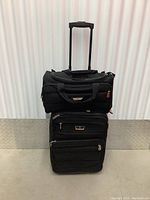 Full view of the two-piece black Air Canada carry-on luggage set, showing larger rolling suitcase with handle and smaller saddle bag attached on top.