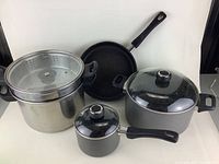 Full set of cookware items including large pot, saucepan, frying pan, and steamer insert