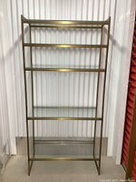 Front view showing the five uniformly spaced tempered glass shelves inside a brass frame.