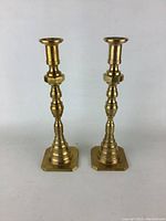 Front view of the two brass candlesticks showing their height and symmetrical design.