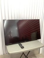 Front view of 39-inch Insignia TV on table with remote in front.