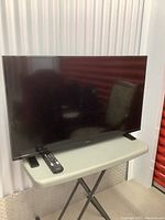 Insignia 39-inch flat-screen TV on a portable table with remote placed in front.