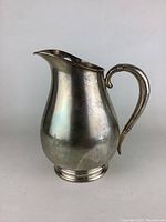 Front view showing pear-shaped body, curved handle and stepped base