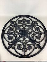 Front view of the round metal outdoor decoration showing the full intricate floral and scroll design in black iron material.