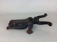 All metal bug-shaped door stopper laying flat, showing front and angled profile.