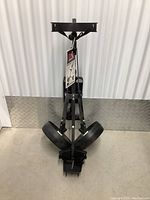 Full view of the black collapsible golf bag cart with two large wheels in a folded upright position.