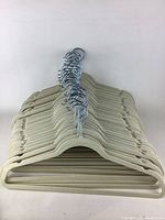 Stacked slim beige velvet clothing hangers with silver metal hooks shown from front angle.