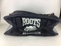 Full side view of the black duffel bag showing the Roots Athletics logo with the beaver design front and center.