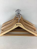 Front view of stacked wooden hangers showing 'Mountain Warehouse' logo on each and metal hooks.