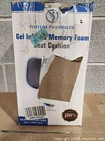 Box of Posture Pro Health Gel Infused Memory Foam Seat Cushion showing severe packaging damage but indicates item is factory sealed and new.