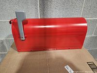 Side view of the red mailbox showing the silver flag and dent on the side.