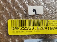 Close-up photo of sticker label on packaged Vanderhoff Shower Caddy, showing model code and brand name.